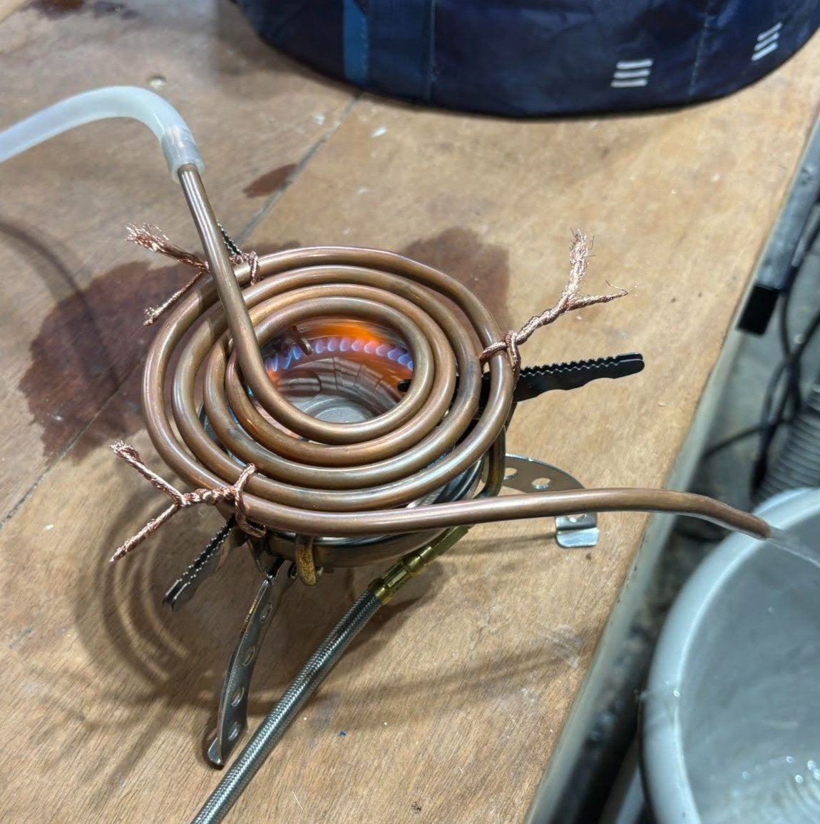 Portable camp stove condensing water heater assembly with copper coil heat exchanger.